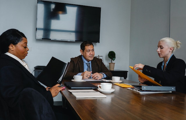 three real estate professionals in a conference room looking over documents